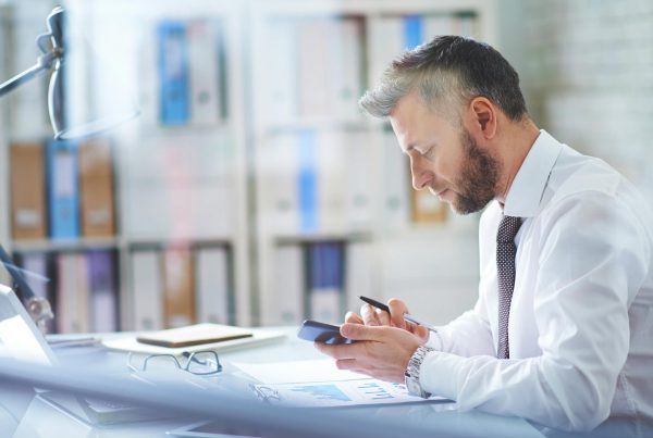 Image of office worker accessing his mobile device in office. Business Mobile Plans and Business Mobile Solutions from Columbus UK. Call 0333 240 7755 for further information.