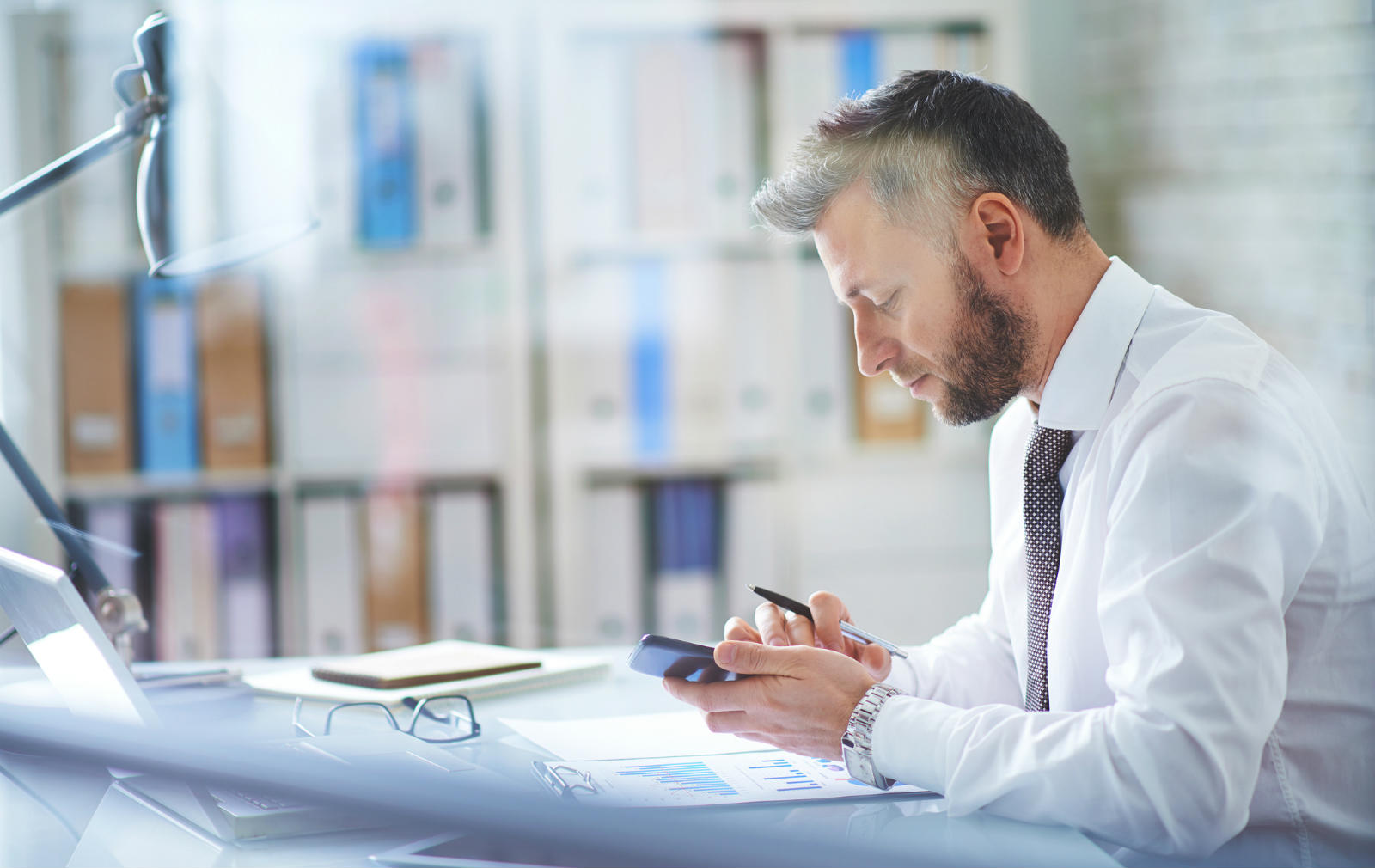 Image of office worker accessing his mobile device in office. Business Mobile Plans and Business Mobile Solutions from Columbus UK. Call 0333 240 7755 for further information.